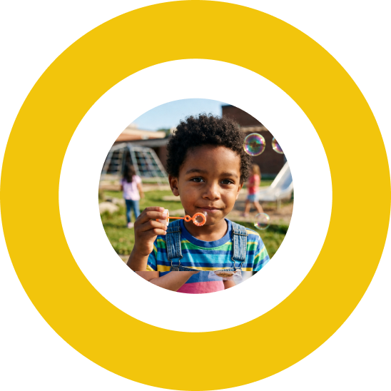 Young boy blowing bubbles on a playground.