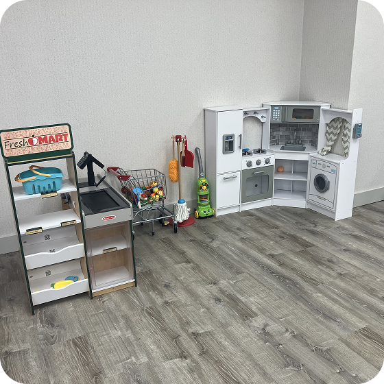 Playroom area featuring a toy grocery store shelf, a checkout counter, a shopping cart, and a toy kitchen set.